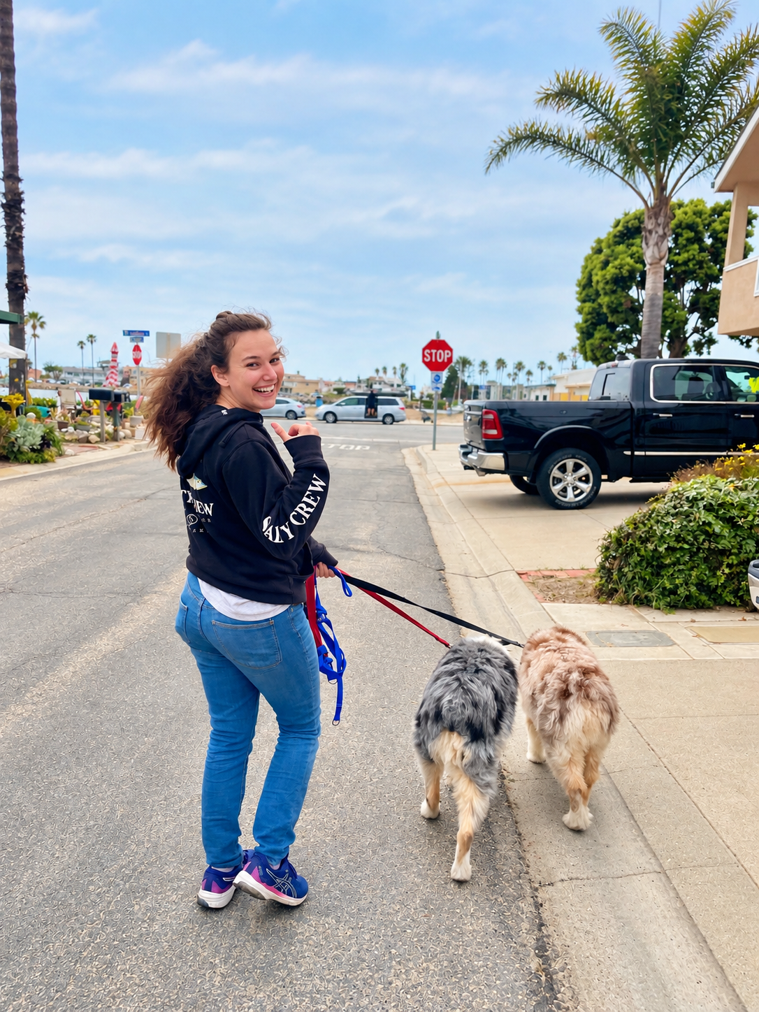 Avela walking two happy dogs on a sunny Ventura County neighborhood street